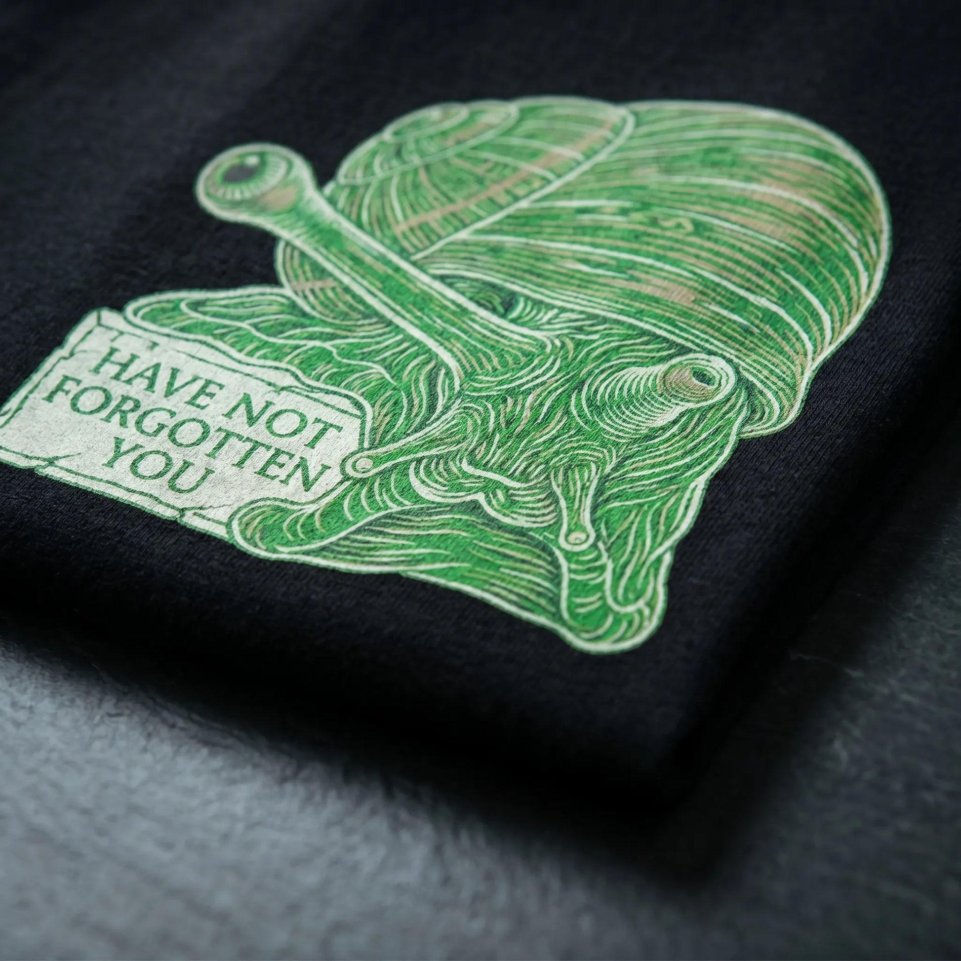 Extreme close-up detail of an immortal snail meme gift tee showing the first-person taunt on soft-hand ringspun cotton fabric with express delivery.