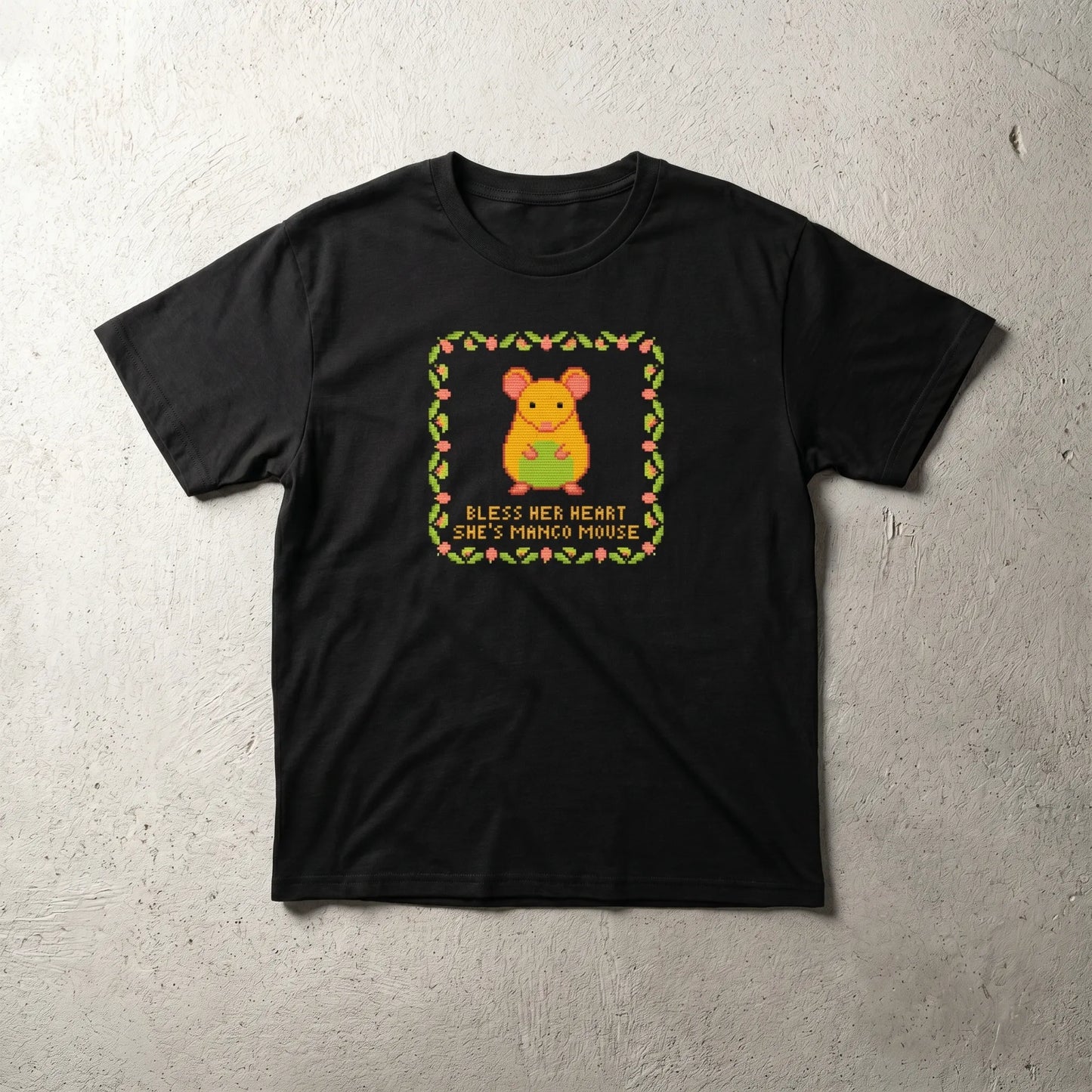 Main front view of the Mangomouse Cross-Stitch Tee featuring the 'bless her heart she's mango mouse' text, a funny polyamory humor in-joke gift for a monogamous sister.