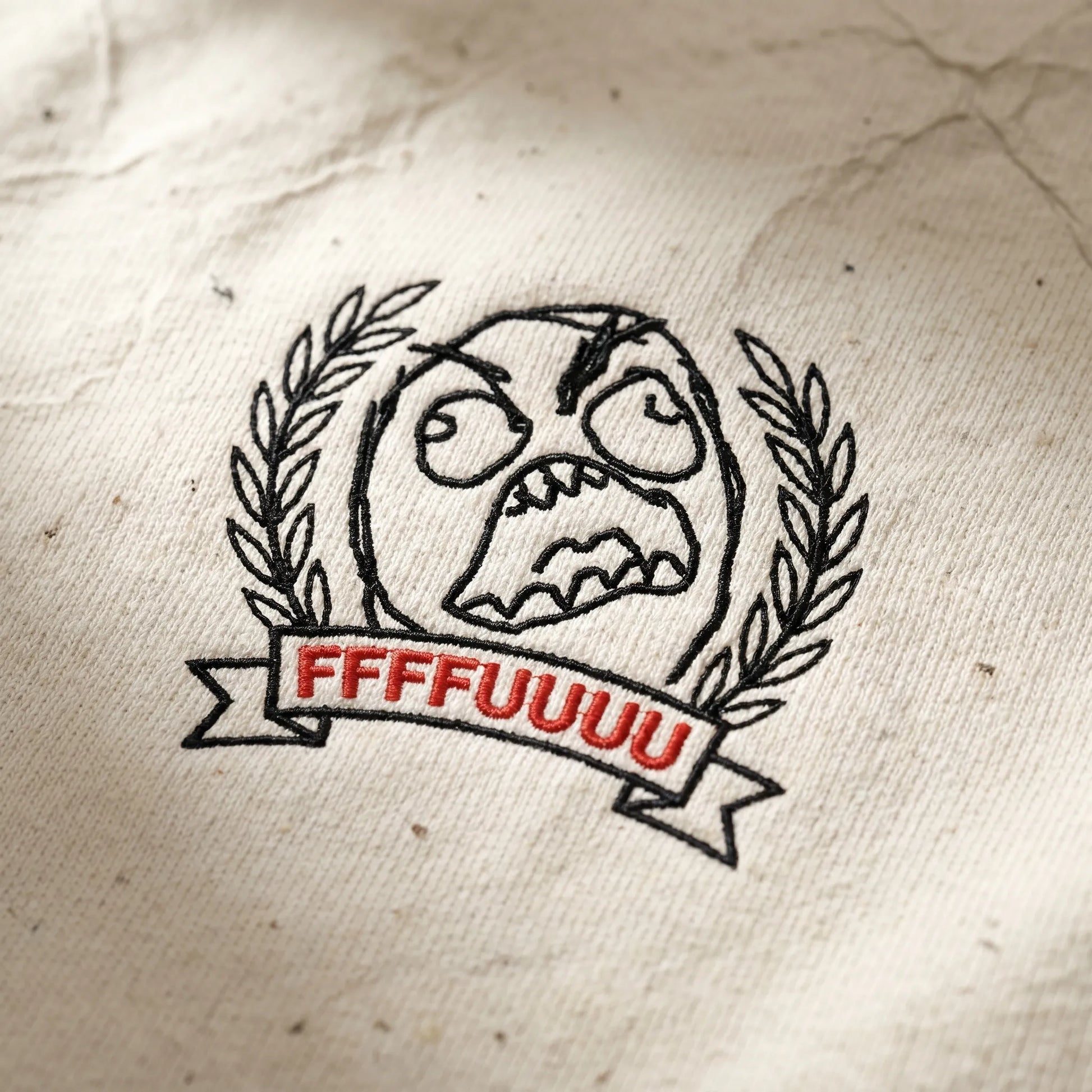 Detailed close-up of the Rage Guy crest tee showing the soft-hand DTG print on 6.0 oz cotton fabric, featuring the redrawn 2008 FFFFUUUU rage face.